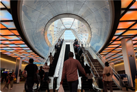 Photo of the Penn Station East End Gateway. People are climbing stairs and escalators under a brightly lit ceiling.