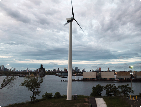 Photo of a wind turbine with NYC skyline visible in the background